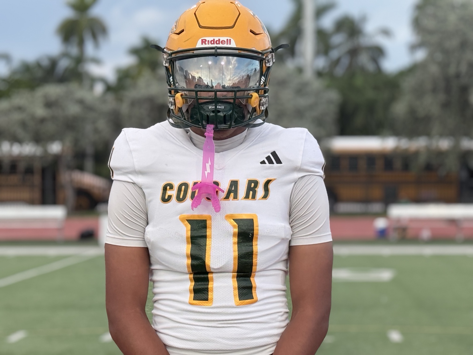 Football player wearing a white Cougars number 11 jersey and gold helmet on the field
